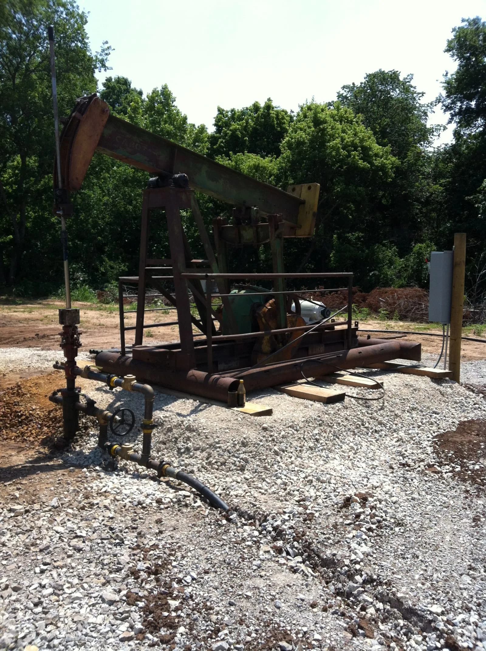 Vertical view of pumpjack equipment and wellhead piping on a lease site