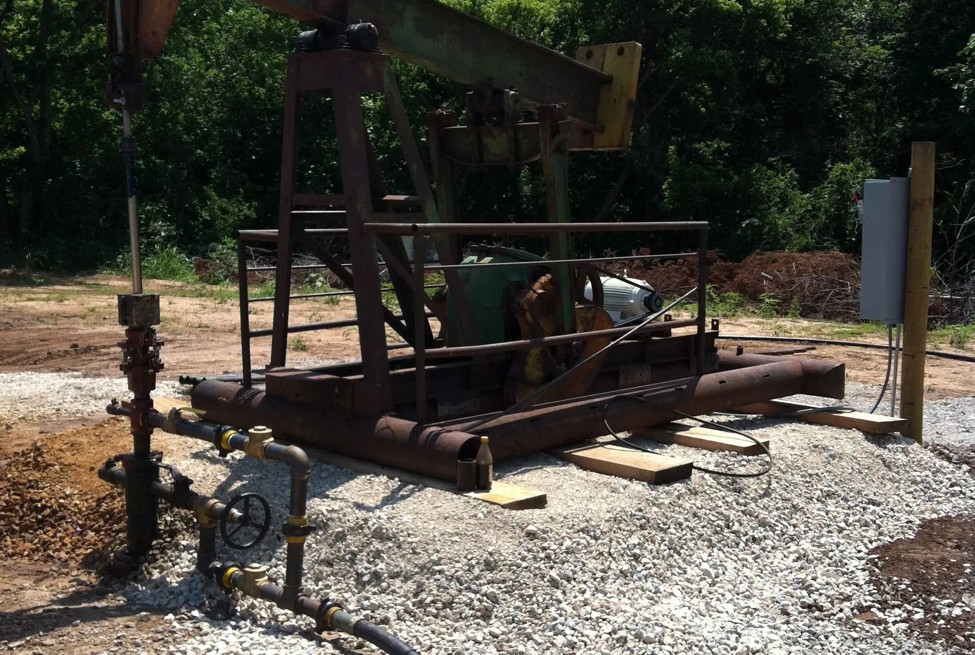Pumpjack, wellhead, and lease equipment on a prepared gravel site