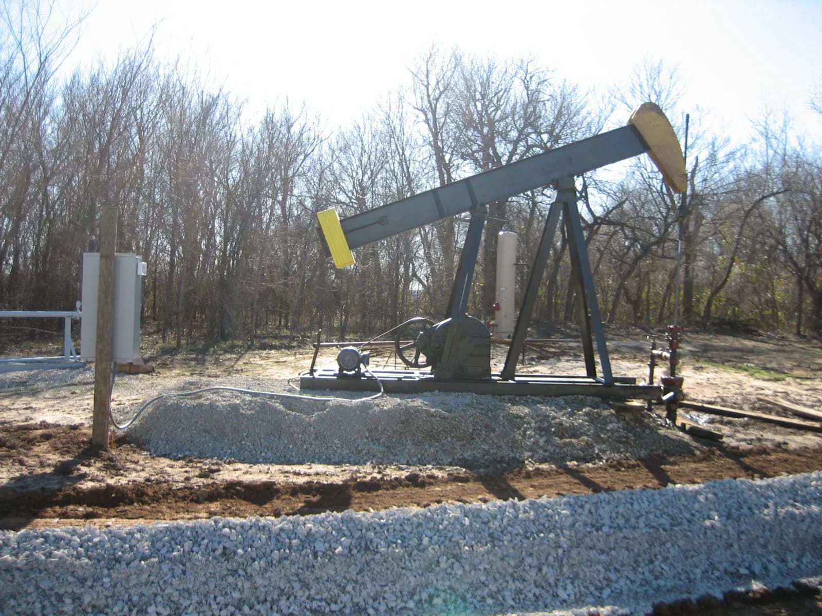 Pumpjack and production equipment on a wooded lease location