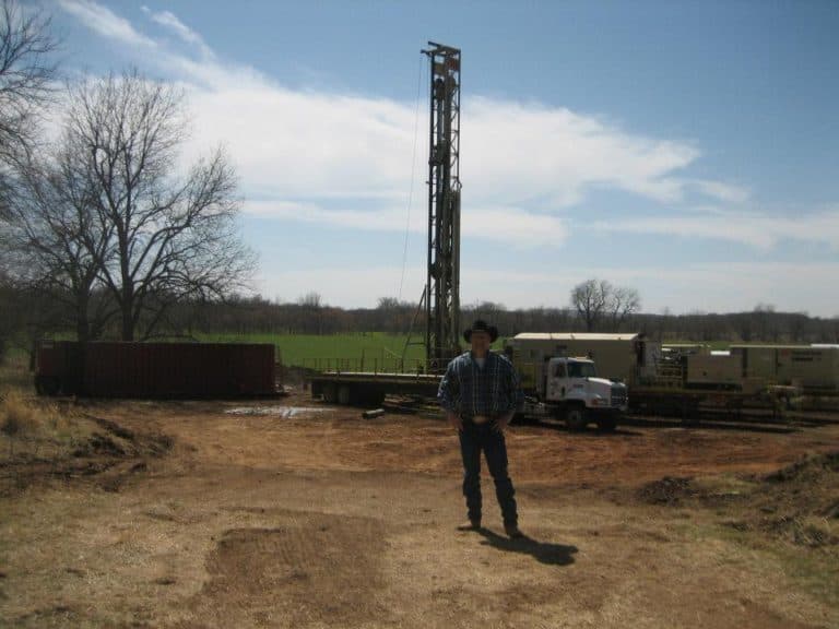 Field operator standing near a workover rig and service equipment
